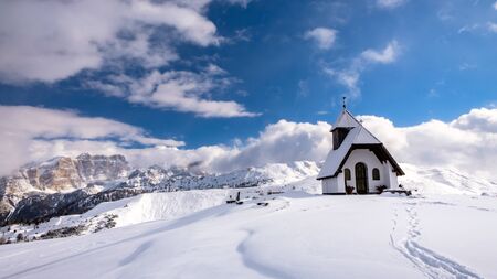 An old church on the top of the mountain in italian alps during winter seasonの写真素材