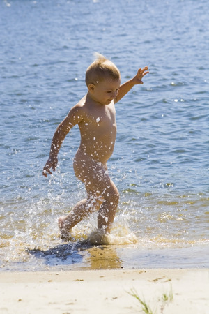 Little boy running in waterの写真素材