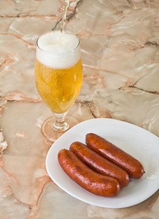 pouring  beer and sausages on plateの写真素材