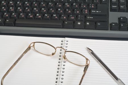 Spectacles with ball pen before keyboardの写真素材