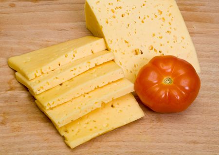 Sliced cheese and tomatoe on wooden boardの写真素材