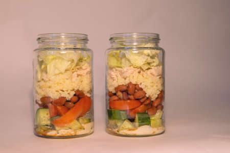 Salad of fresh vegetables, beans, chicken fillet, couscous in two glass jarsの写真素材