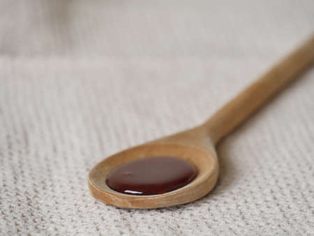 Wooden spoon with dark honey on a beige towel narrow focusの写真素材