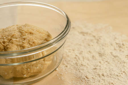 Cottage cheese dough in a glass dish on the table with scattered white flourの写真素材