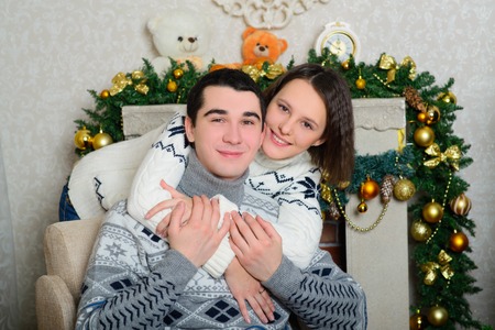 Nice love couple sitting on carpet in front of fireplace. Woman and man celebrating Christmasの写真素材