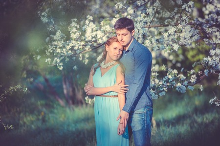 Young beautiful couple in love among apple trees in blossomの写真素材