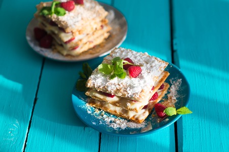 close up of Mille-feuille puff pastry with raspberries on a blue Boardの写真素材
