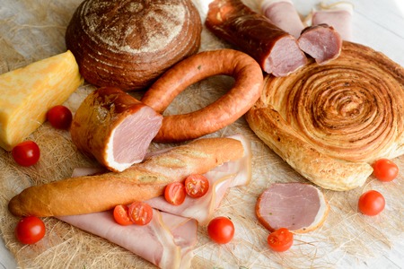 cold cuts on a wooden Board with vegetables and breadの写真素材