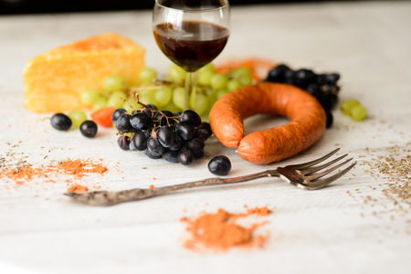 a glass of wine and grapes next to cheese and sausagesの写真素材