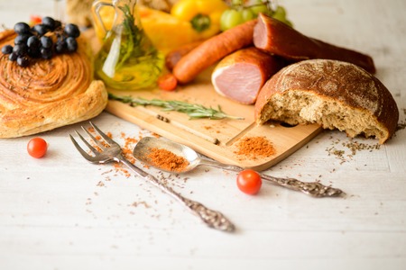 Assorted meat products, including ham and sausages,cheese,grapes,vegetables and spices on wooden tableの写真素材