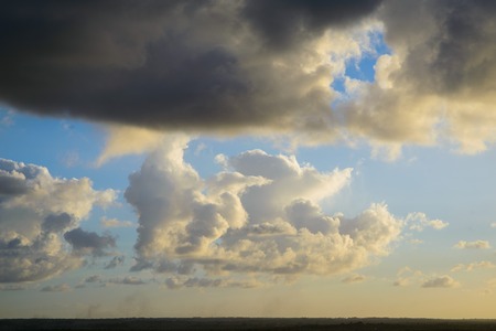 Cumulus clouds on sunset sky, with the sun setting downの写真素材