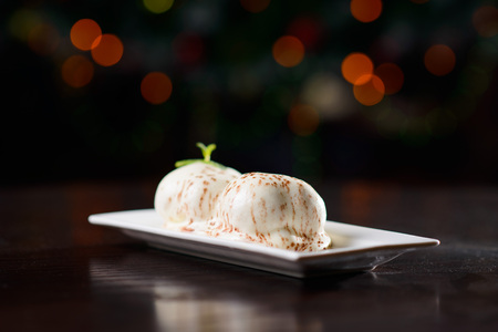 Cream puff or profiterole with filling, powdered sugar topping and mintの写真素材
