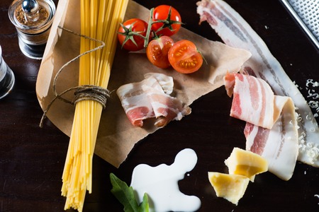 Food ingredients for Italian spaghetti, tomatoes and bacon and milk on black backgroundの写真素材