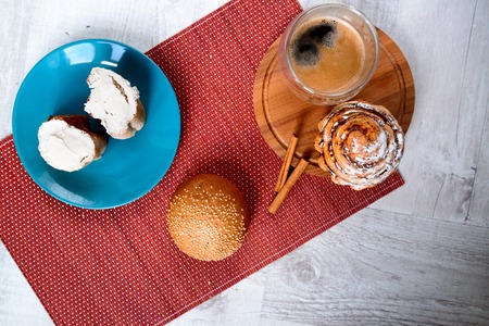 Cup of coffee served with biscuits and buns on wooden backgroundの写真素材
