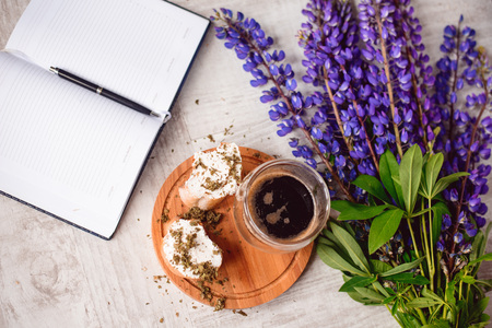 Note with a pen, a calendar and a Cup of coffee served with bruschetta, lupins flowers on wooden tableの写真素材