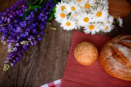 Close up on traditional bread on the table, next to flowers daisies and lupinsの写真素材