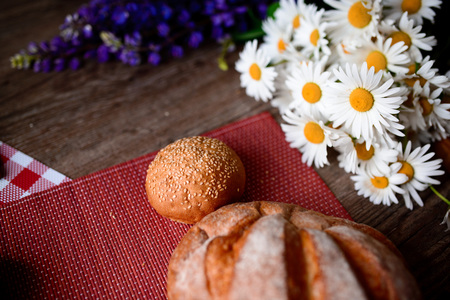 Close up on traditional bread on the table, next to flowers daisies and lupinsの写真素材