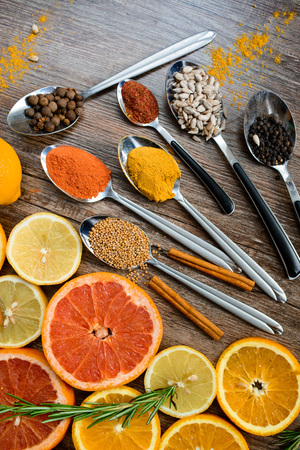 the fragrance of spices, red pepper, black pepper, mustard,sunflower seeds ,and orange slices of citrus fruits on dark wooden background of the table. Closeup top viewの写真素材