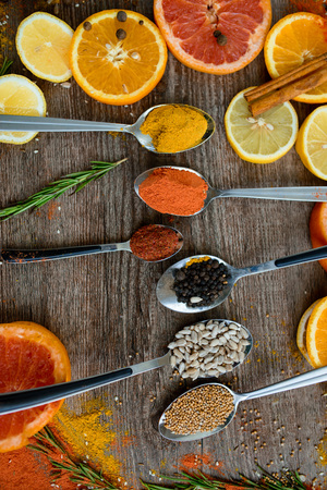 the fragrance of spices, red pepper, black pepper, mustard,sunflower seeds ,and orange slices of citrus fruits on dark wooden background of the table. Closeup top viewの写真素材