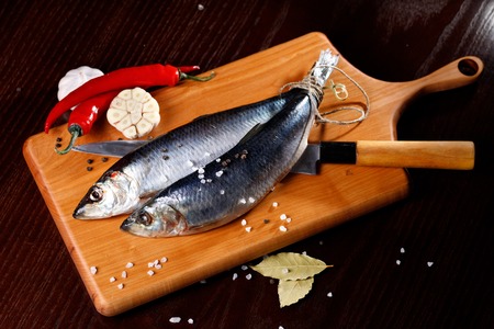 two herring with red pepper and garlic on a cutting Board with a knife. Rustic style.の写真素材