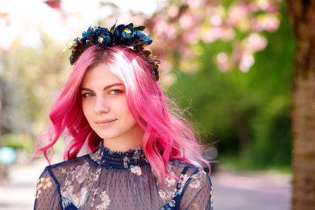 young beautiful girl with pink hair standing near a tree with flowers, pink flowers, spring, sun, happiness, tendernessの写真素材
