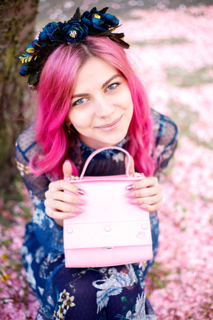 young beautiful girl with pink hair standing near a tree with flowers, pink flowers, spring, sun, happiness, tendernessの写真素材