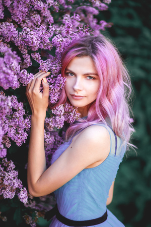 Beautiful girl with pink hair, enjoying the Lilac garden. cheerful teenager walking in the fresh air. soft light style color.の写真素材