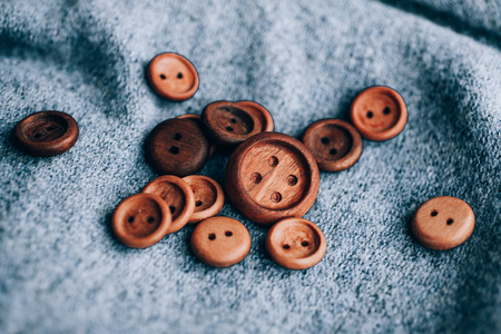Vintage wooden buttons on handwoven cotton fabric. Natural side lighting to emphasize textures.