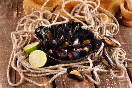 Boiled mussels in copper dish for cooking on wooden background close-upの写真素材