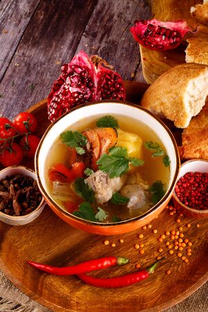 Uzbek shurpa soup in a bowl with two hot peppersの写真素材