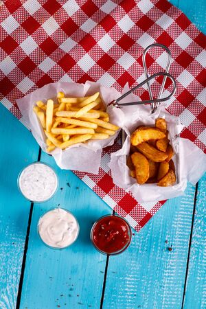 French fries and rustic potatoes next to the sauce on the table backgroundの写真素材