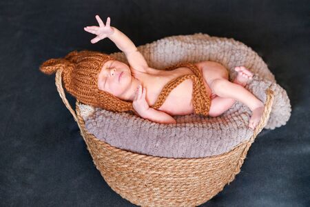 A newborn boy in a knitted hat, sleeping on a blanket lies in a basket. top view.の写真素材