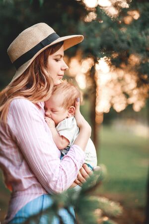 A mother embraces her child in nature against the background of the setting sun