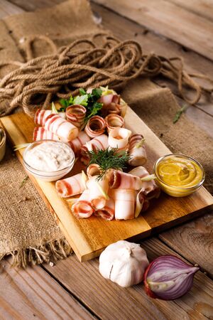 Bacon on a wooden Board, next sauce, onion, on a wooden table backgroundの写真素材
