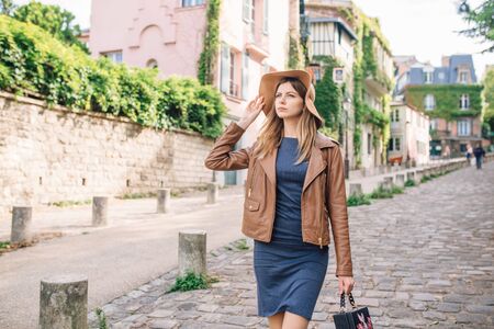 A beautiful young woman in a brown jacket walks in the early morning on the famous Montmartre hill in Paris, Franceの写真素材