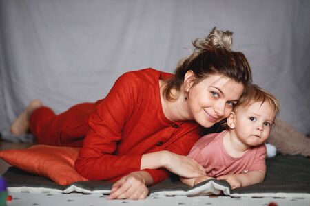 A young mother with her one-year-old little son, a warm and cozy scene.の写真素材