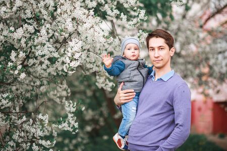 A father and a little boy are having fun near the cherry blossom trees. Flowers bloom in the spring...