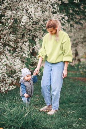happy mother and son play against the background of a flowering tree. Spring, mother's day. Happy familyの写真素材