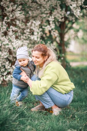 happy mother and son play against the background of a flowering tree. Spring, mother's day. Happy familyの写真素材