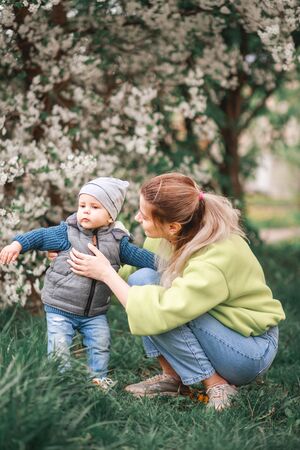 happy mother and son play against the background of a flowering tree. Spring, mother's day. Happy familyの写真素材