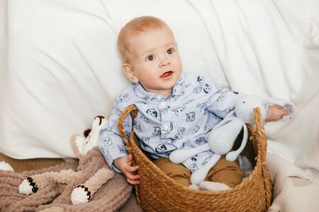 A small boy is sitting in a wicker basket on a light background