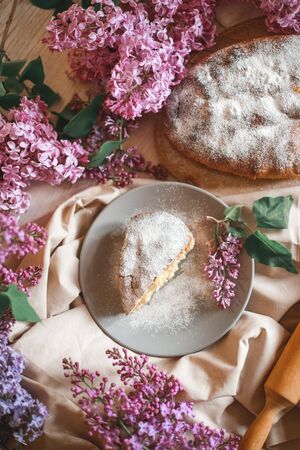 Homemade Apple pie on a wooden table next to a bowl of lilacs. Gentle toning. Selective focus.の写真素材