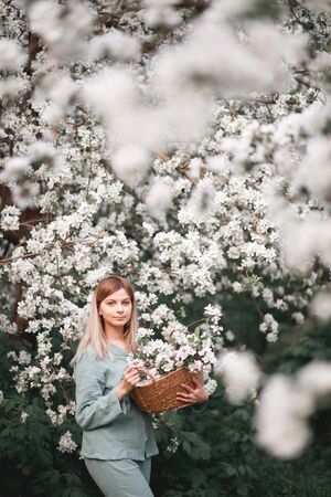 girl with a basket of flowers blooming Apple trees in springの写真素材