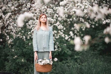 girl with a basket of flowers blooming Apple trees in springの写真素材