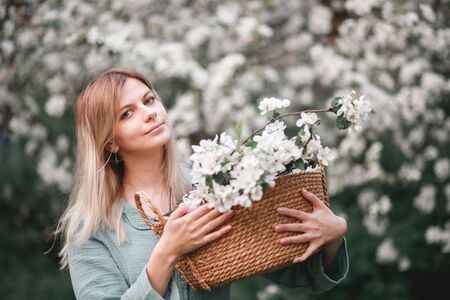 girl with a basket of flowers blooming Apple trees in springの写真素材