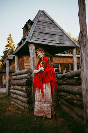A beautiful Slavic girl with long blonde hair and brown eyes in a white and red embroidered suit is...