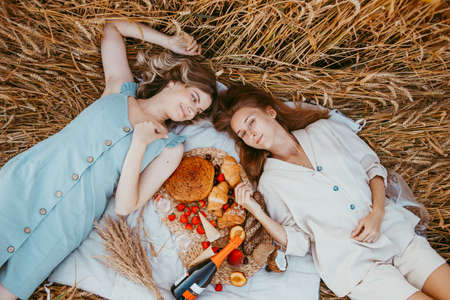 Happy friends on the Golden field. Young girls on a picnic in a yellow wheat field
