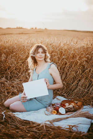 portrait of a girl of model appearance in wheat, a girl sitting on a wheat field on a Sunny dayの写真素材