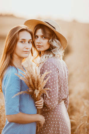 happy friends in a wheat field. girls on a picnic in a field near wheat ears at sunset.の写真素材