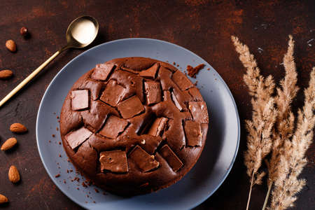 Chocolate cake with chocolate pieces on a brown table background